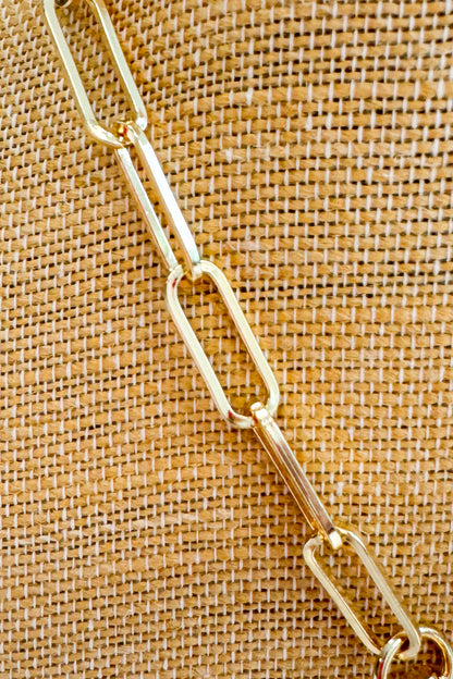 Gold chain on a textured brown fabric background