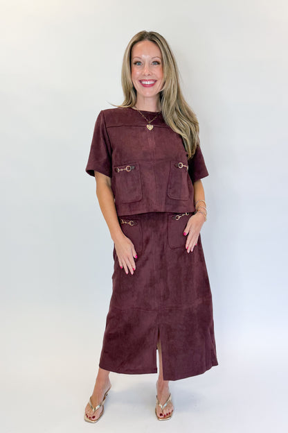 Front view of woman wearing Swagger Boutique’s Merlot Suede Horsebit Pocket Top &amp; Skirt by Entro against white studio background.