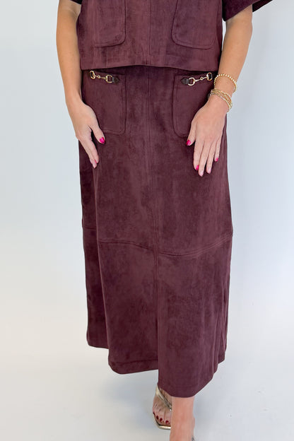 Front detail view of woman wearing Swagger Boutique’s Merlot Suede Horsebit Pocket Top &amp; Skirt by Entro against white studio background.