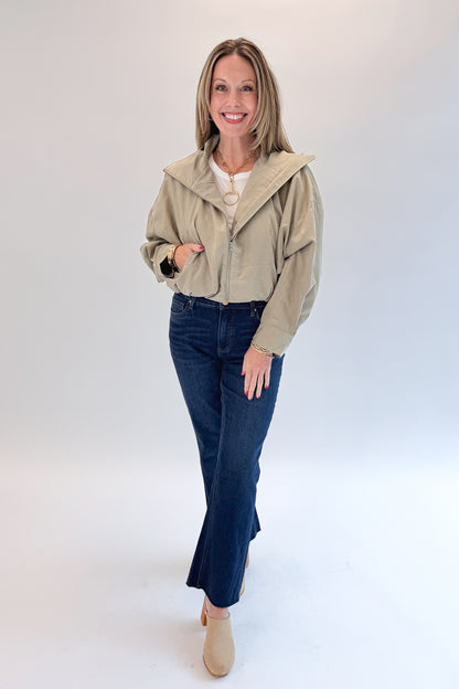 Front view of woman wearing Swagger Boutique’s Khaki Bubble Hem Bomber Jacket with jeans against white studio background.