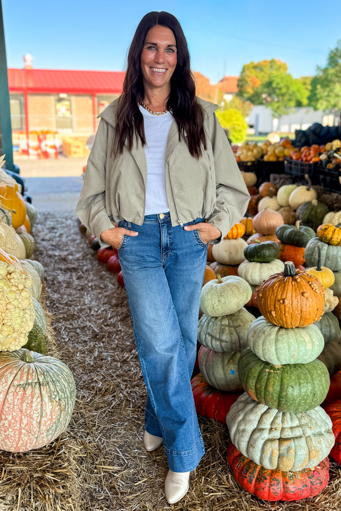 Front view of woman wearing Swagger Boutique’s Khaki Bubble Hem Bomber Jacket with jeans at a pumpkin patch.