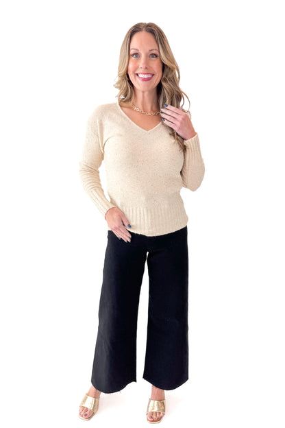 Front view of woman wearing Cream With Gold Sequin Sweater with jeans against white studio background.