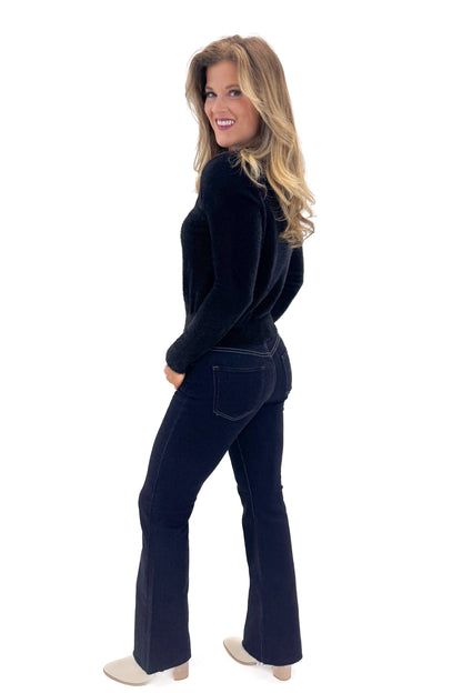 Side view of woman wearing Black With Rhinestone Buttons Eyelash Cardigan with jeans against white studio background. 