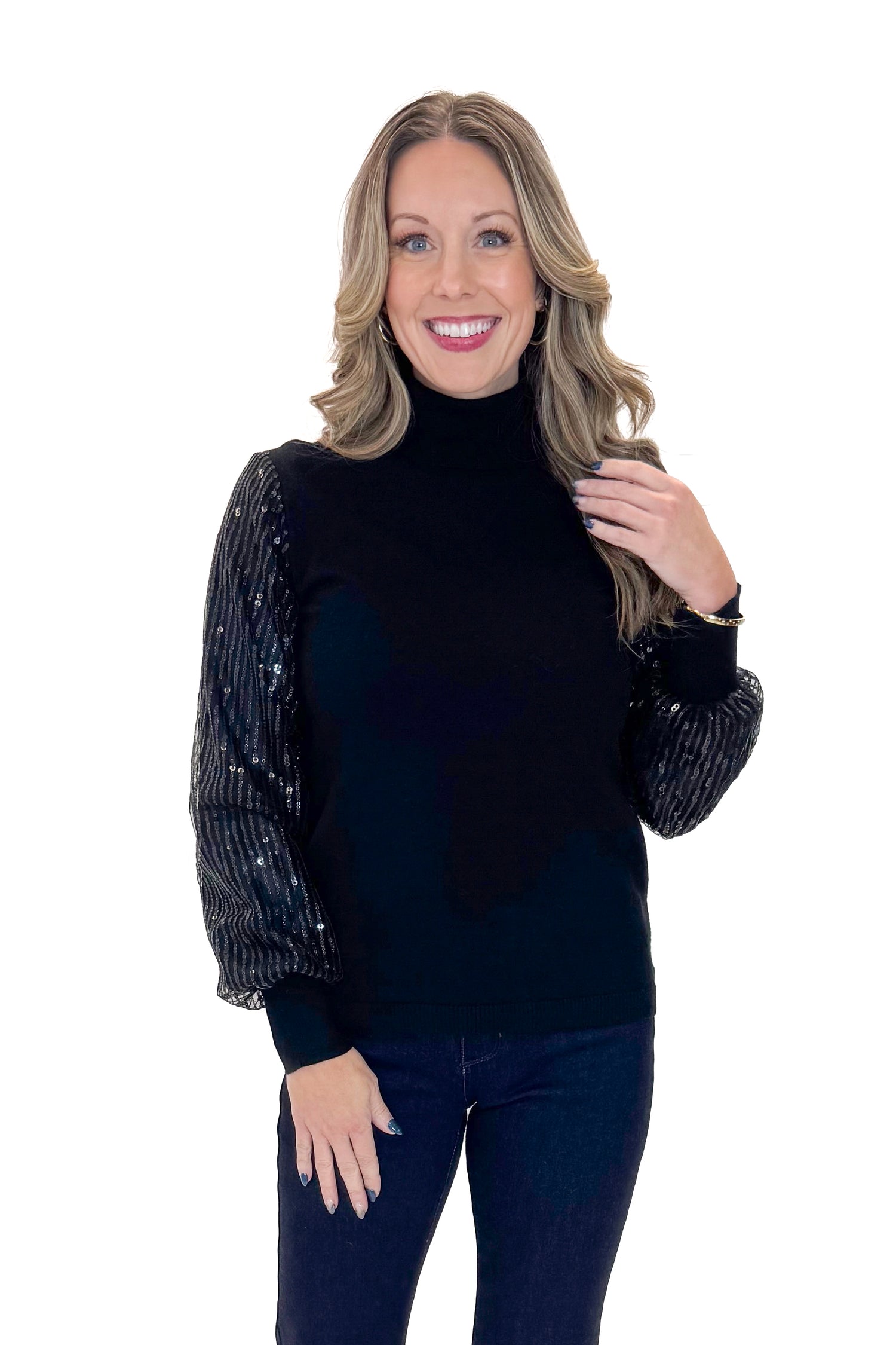 Front view of woman wearing Black Sequined Sleeve Turtleneck Sweater with jeans against white studio background.