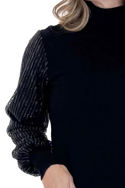 Front detail view of woman wearing Black Sequined Sleeve Turtleneck Sweater against white studio background.