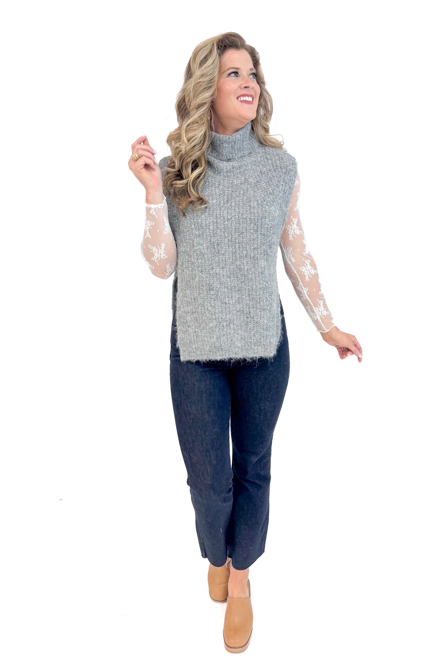 Front view of woman wearing Grey Turtleneck Sweater Vest and blue jeans.