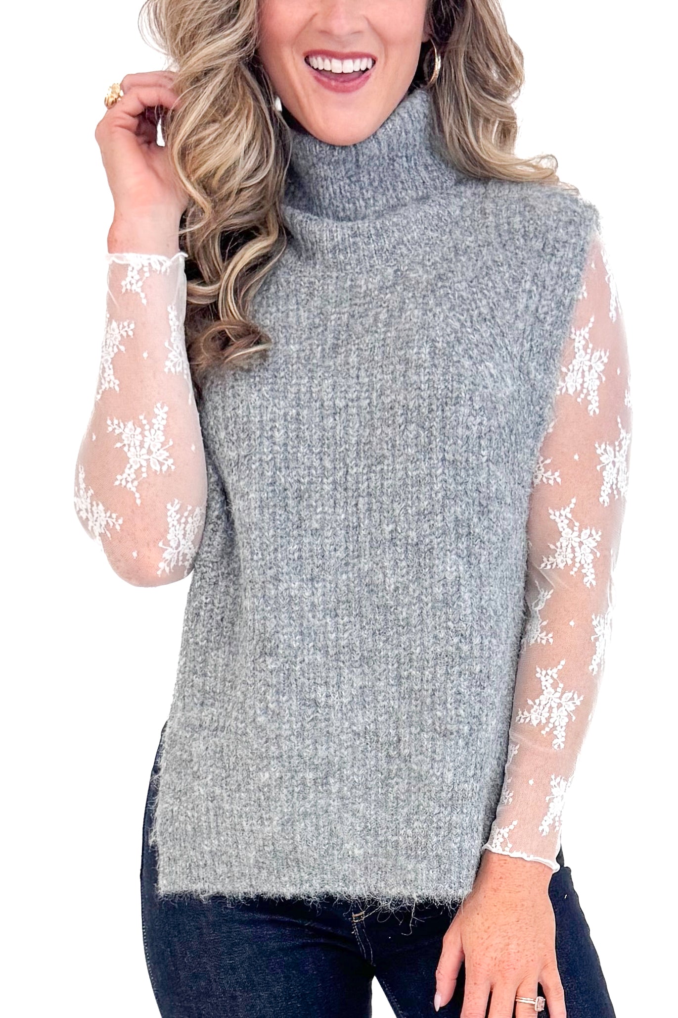 Front detail view of woman wearing Grey Turtleneck Sweater Vest and blue jeans.