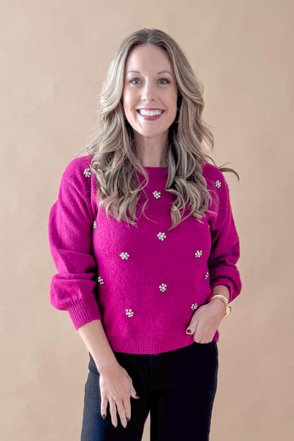 Front view of woman wearing Magenta Rhinestone Detail Sweater with jeans against tan studio background.