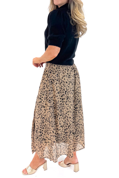 Side view of woman wearing black sweater with Beige Leopard Button Detail Skirt against white studio background.