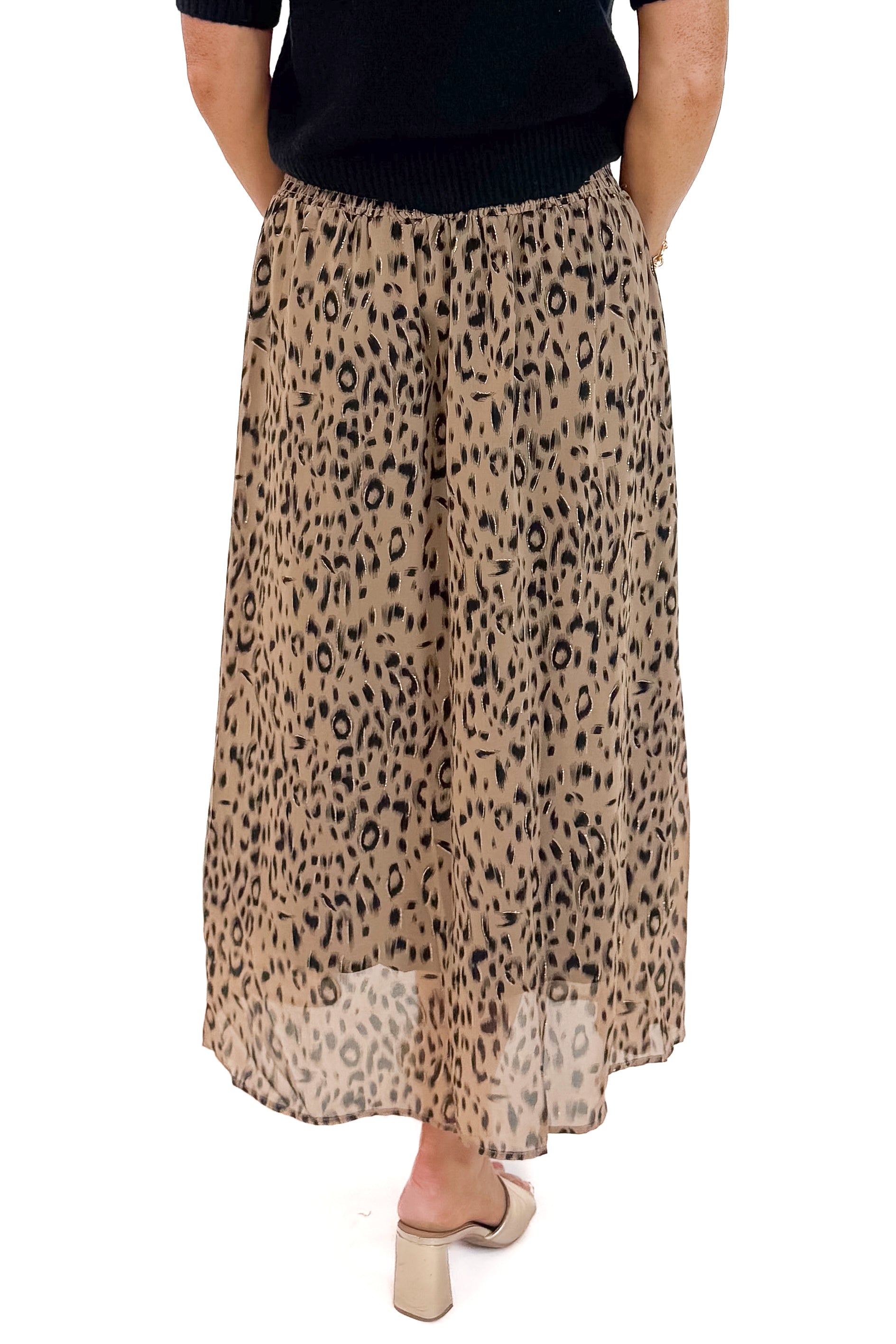 Back view of woman wearing black sweater with Beige Leopard Button Detail Skirt against white studio background.