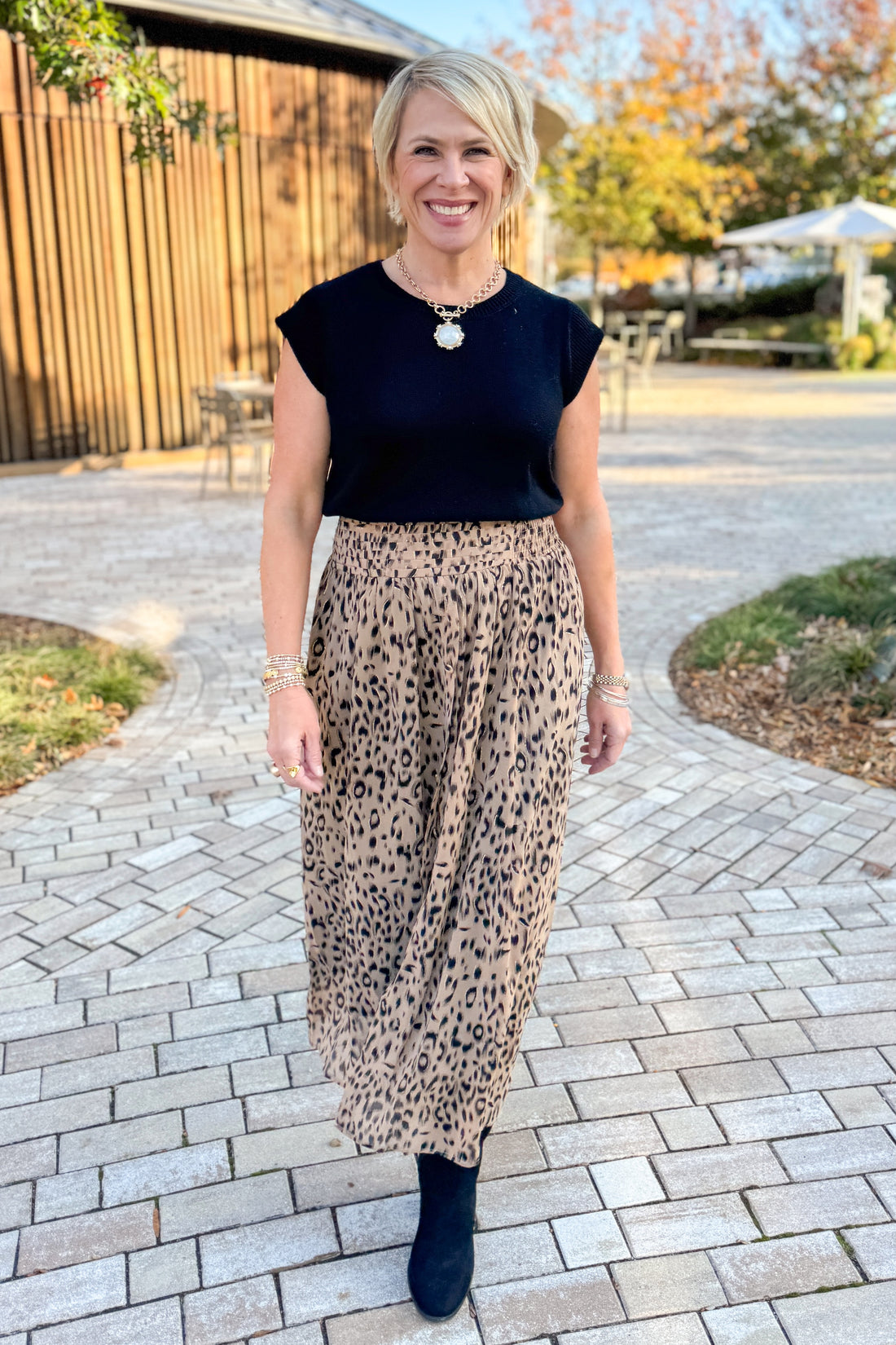 Front view of woman wearing black sweater with Beige Leopard Button Detail Skirt outside.