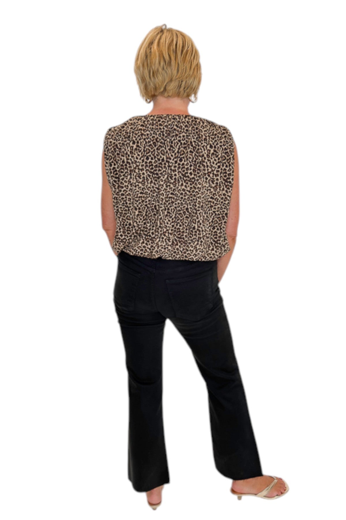 Back view of woman wearing Swagger Boutique’s Leopard Bubble Hem Top with jeans against white studio background.