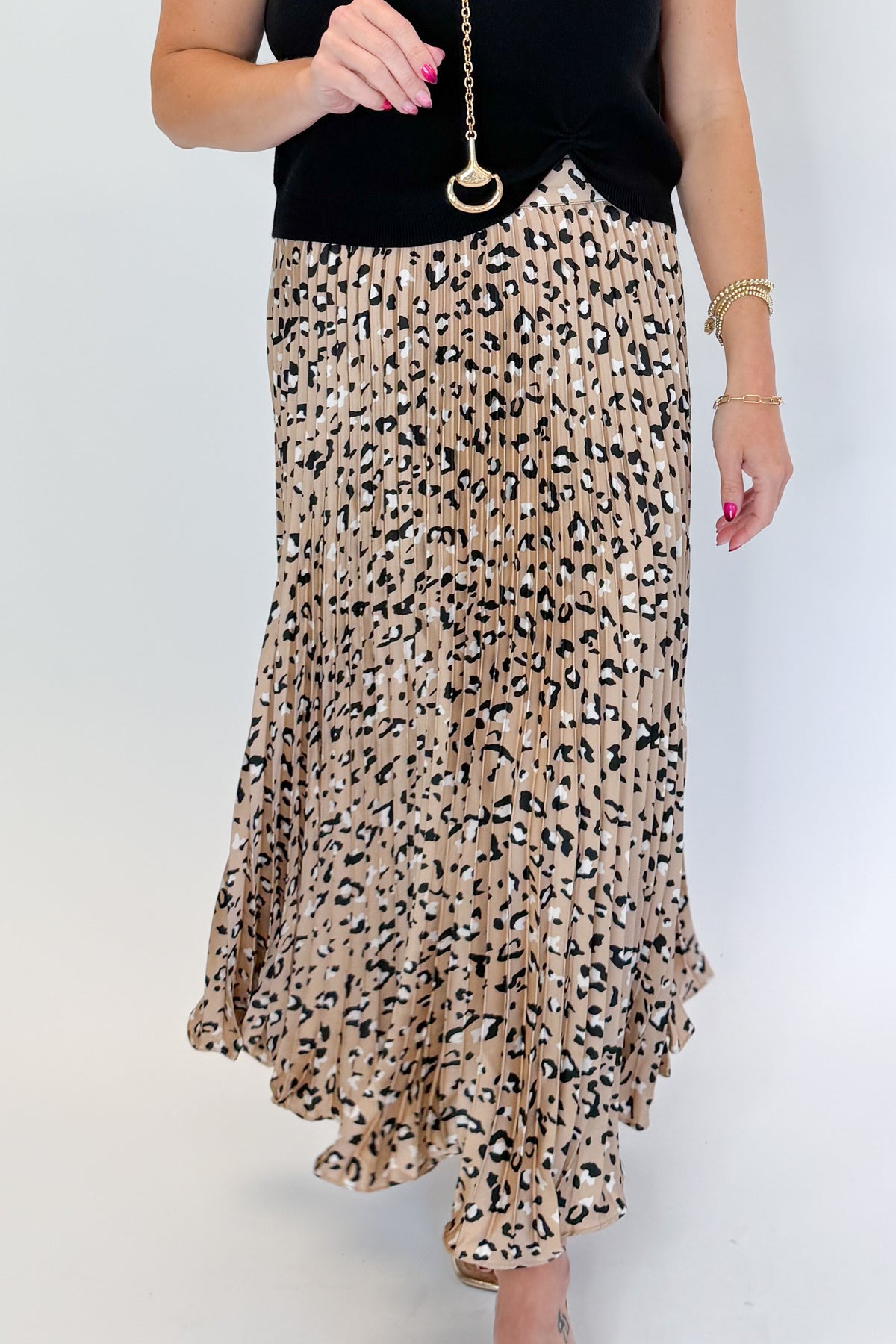 Front view of woman wearing Swagger Boutique’s Leopard Pleated Skirt &amp; Black Short Sleeve Twist Detail Sweater against white studio background.