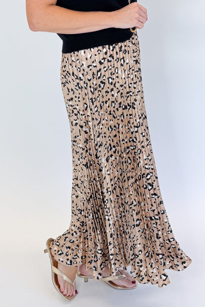 Side detail view of woman wearing Swagger Boutique’s Leopard Pleated Skirt &amp; Black Short Sleeve Twist Detail Sweater against white studio background.