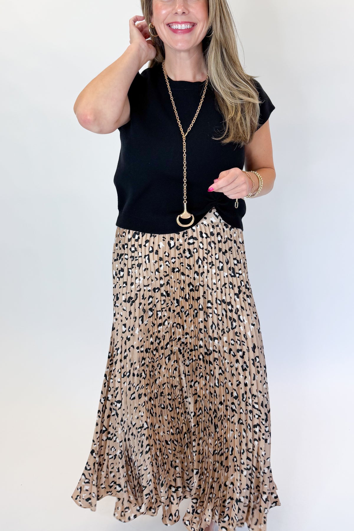 Front view of woman wearing Swagger Boutique’s Leopard Pleated Skirt &amp; Black Short Sleeve Twist Detail Sweater against white studio background.