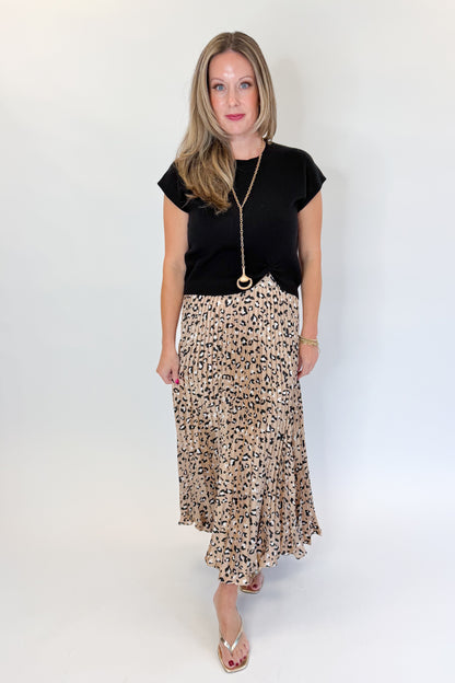 Front view of woman wearing Swagger Boutique’s Leopard Pleated Skirt &amp; Black Short Sleeve Twist Detail Sweater against white studio background.