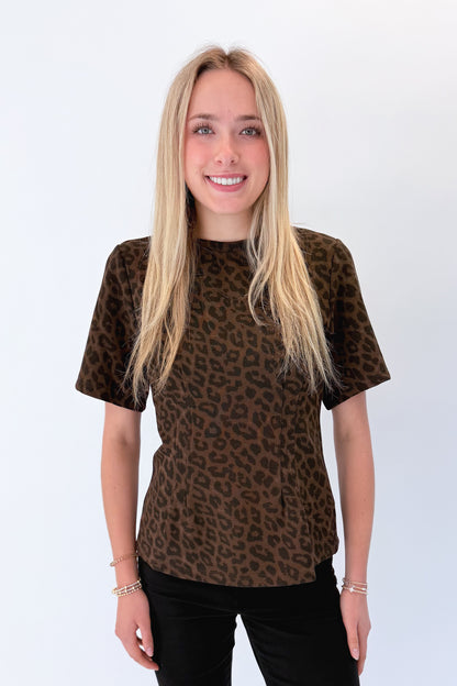 Front view of woman wearing Swagger Boutique’s Leopard Pleated Top with jeans against white studio background.