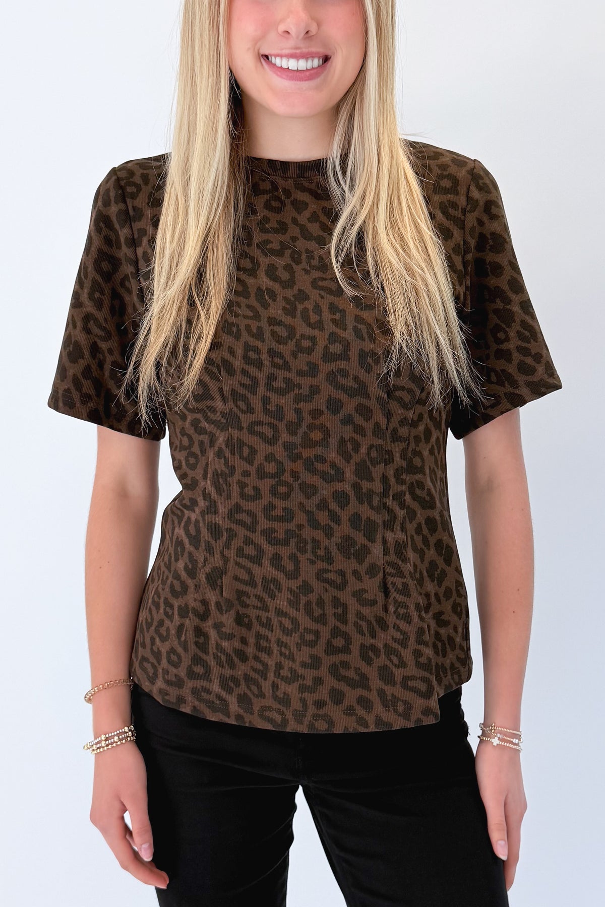 Front detail view of woman wearing Swagger Boutique’s Leopard Pleated Top with jeans against white studio background.