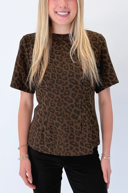 Front detail view of woman wearing Swagger Boutique’s Leopard Pleated Top with jeans against white studio background.