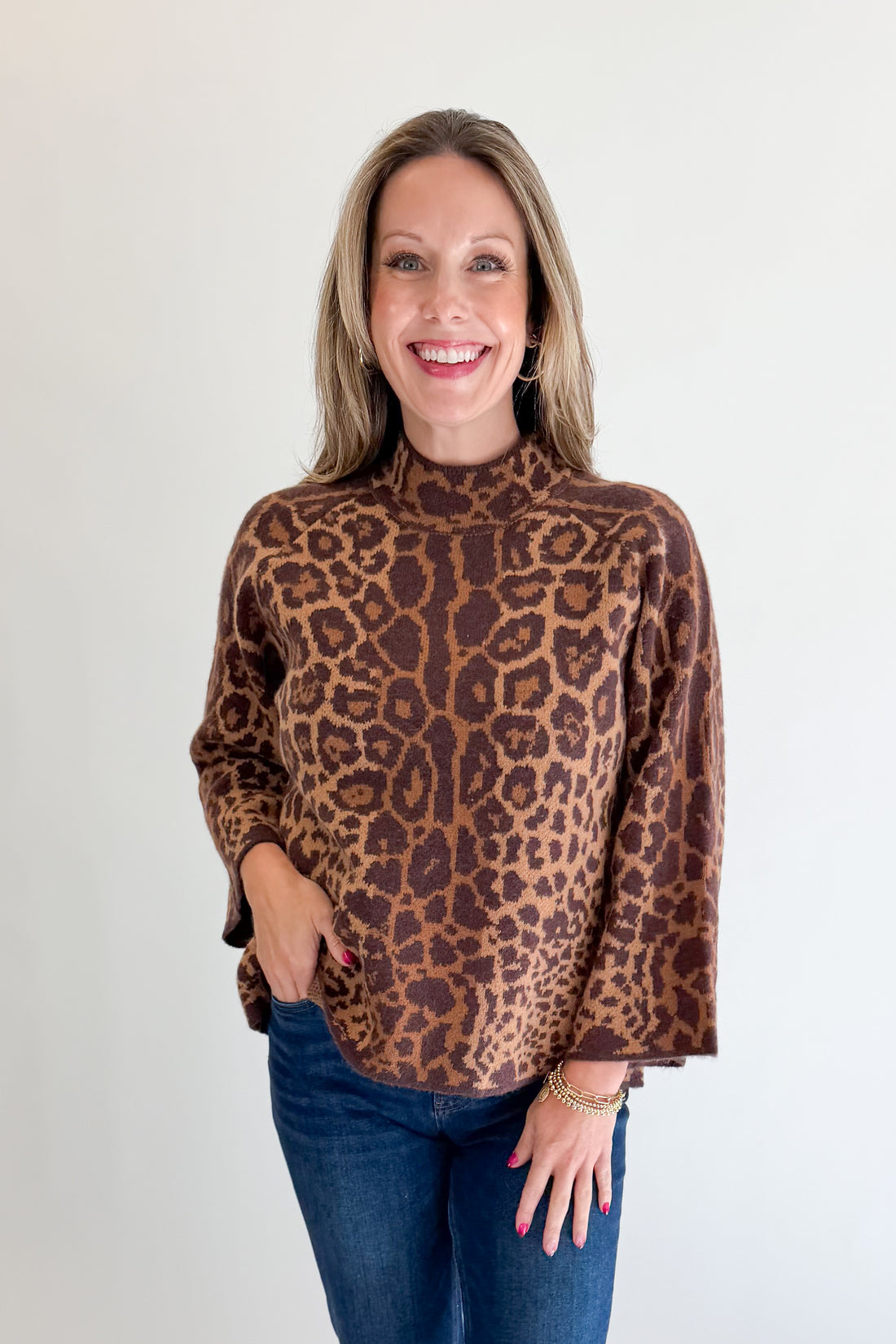 Front view of woman wearing Swagger Boutique’s Leopard Print Mock Neck Sweater by Entro with jeans against white studio background.