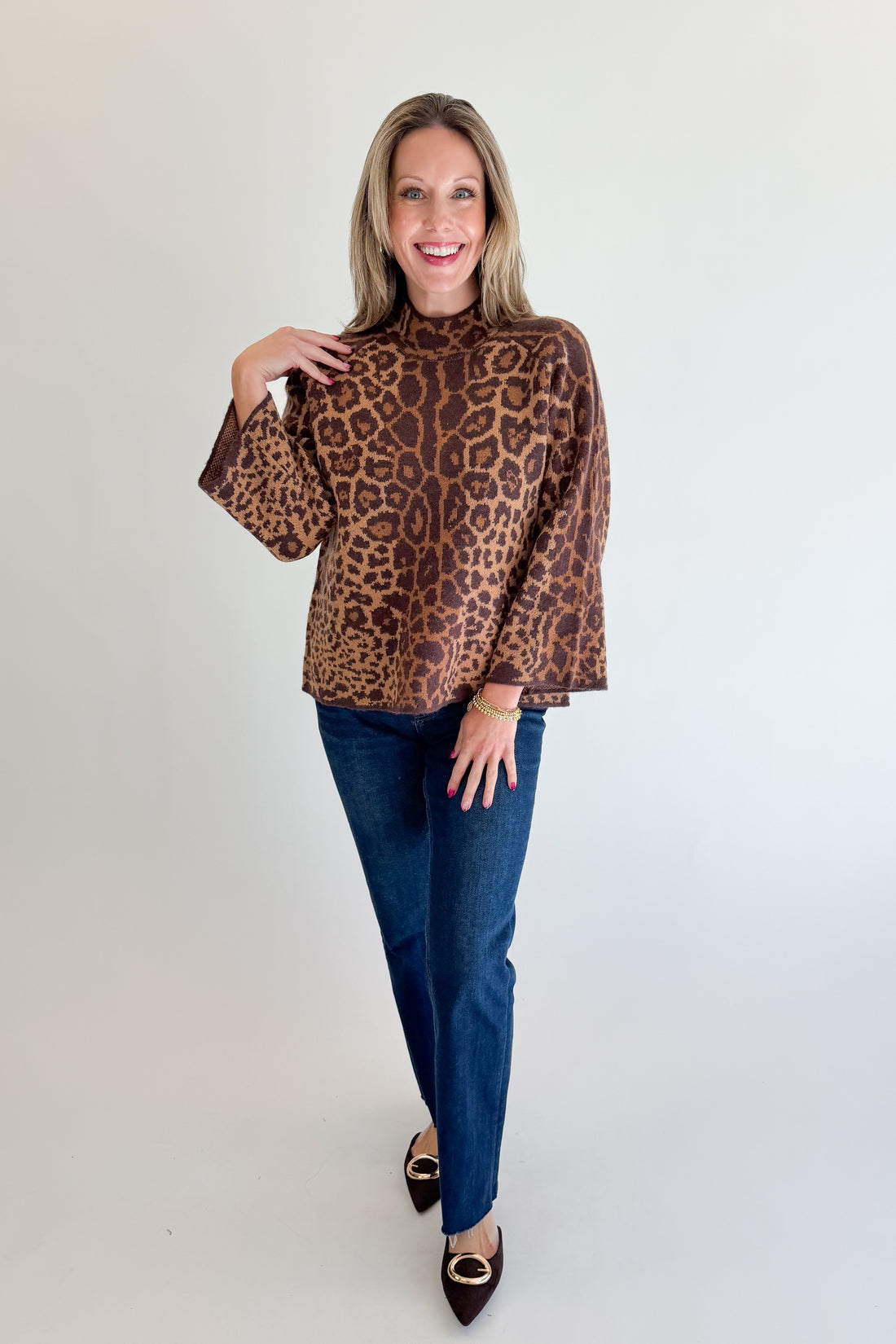 Front view of woman wearing Swagger Boutique’s Leopard Print Mock Neck Sweater by Entro with jeans against white studio background.