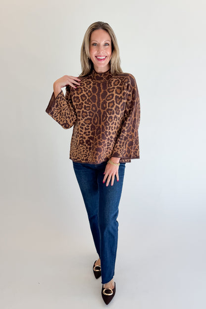 Front view of woman wearing Swagger Boutique’s Leopard Print Mock Neck Sweater by Entro with jeans against white studio background.