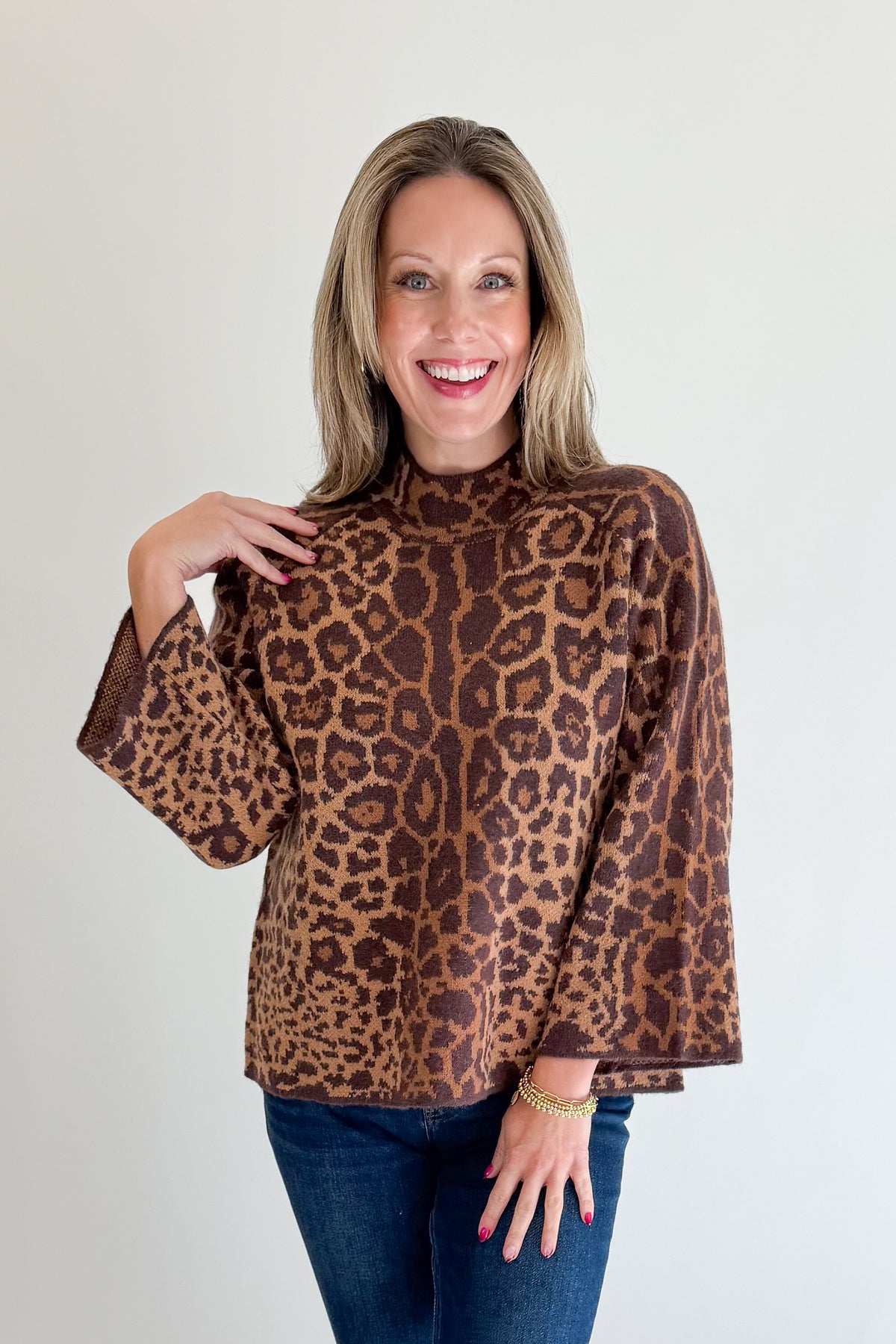 Front view of woman wearing Swagger Boutique’s Leopard Print Mock Neck Sweater by Entro with jeans against white studio background.