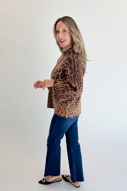 Side view of woman wearing Swagger Boutique’s Leopard Print Mock Neck Sweater by Entro with jeans against white studio background.