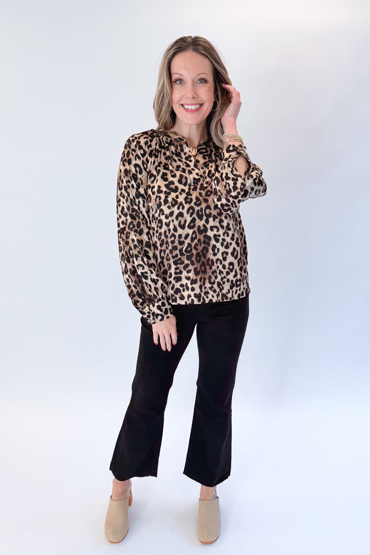 Front view of woman wearing Swagger Boutique’s Leopard Print Silky Top with jeans against white studio background.