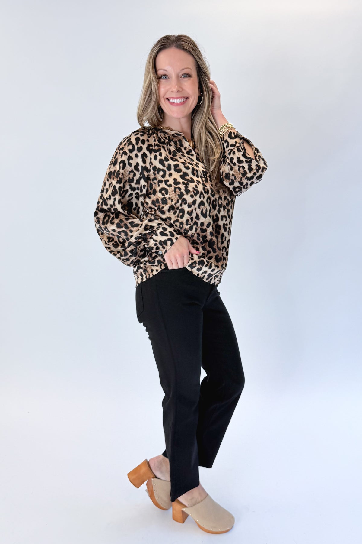 Side view of woman wearing Swagger Boutique’s Leopard Print Silky Top with jeans against white studio background.