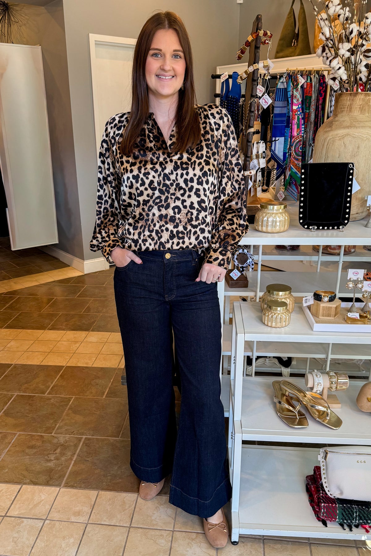 Front view of woman wearing Swagger Boutique’s Leopard Print Silky Top with jeans standing at the store.