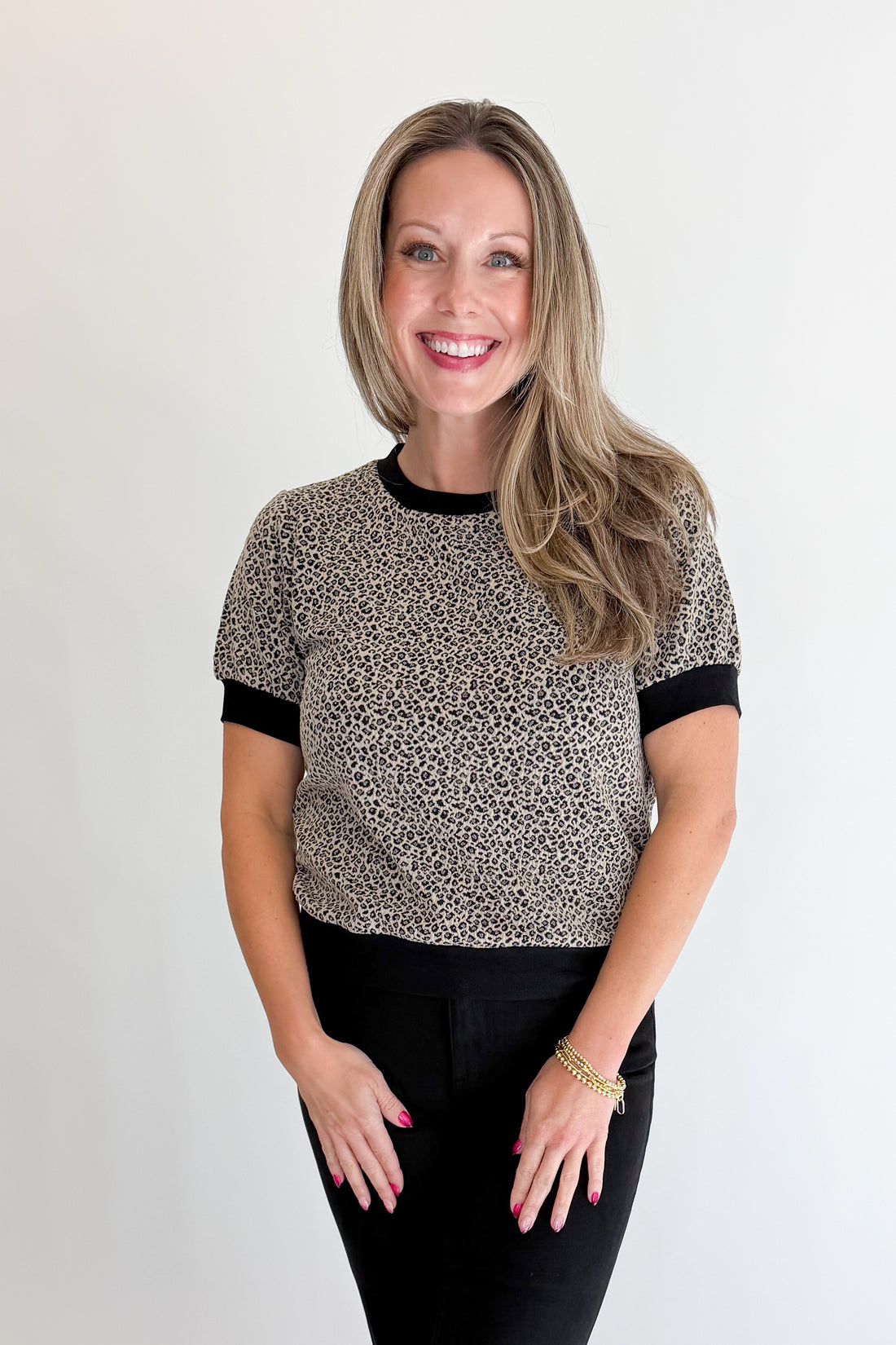 Front view of woman wearing Swagger Boutique’s Leopard Textured Short Sleeve Top with jeans against white studio background.