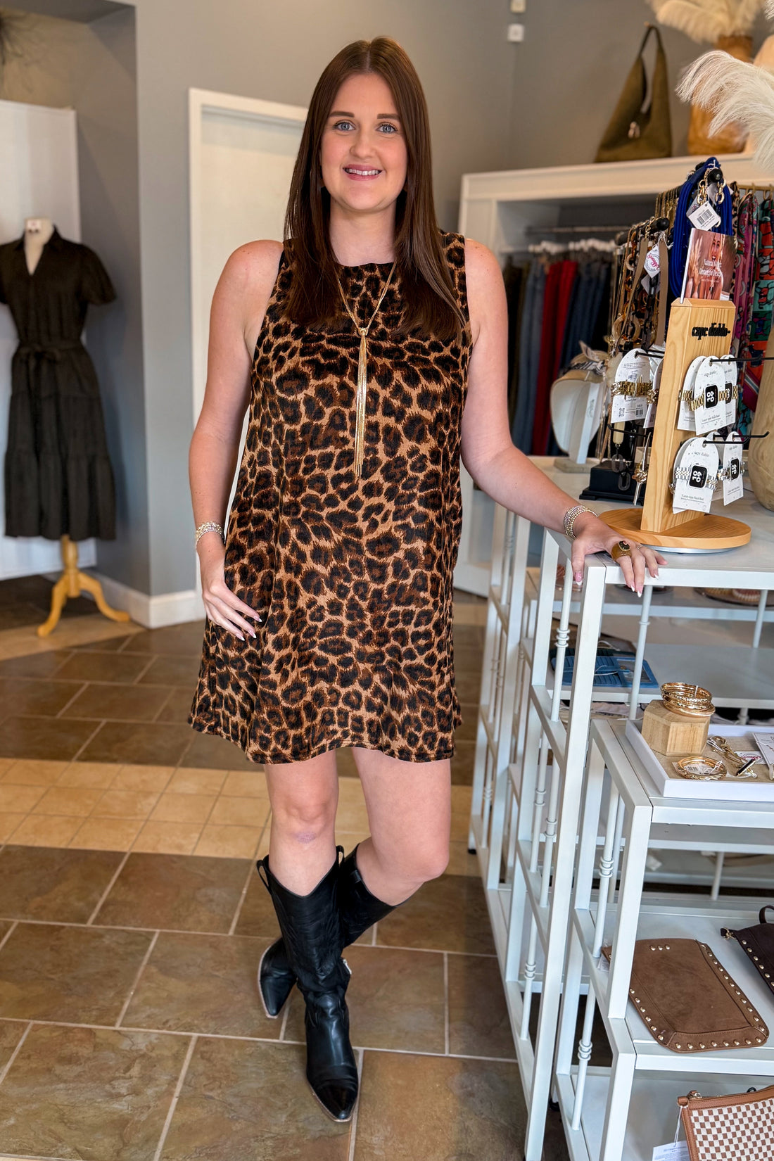 Front view of women wearing Swagger Boutique’s Leopard Velvet Mini Dress with boots standing at the store.