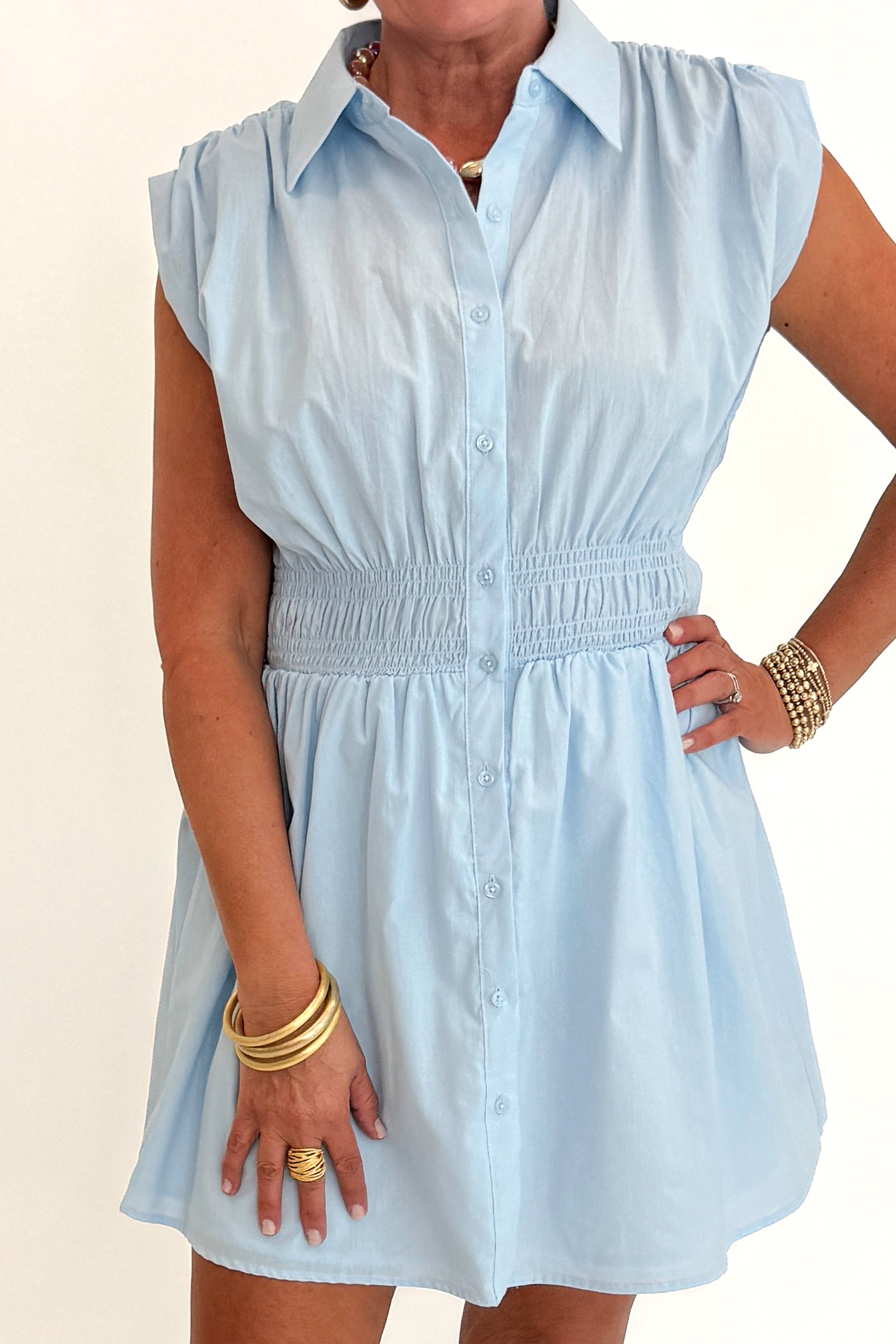 Front detail view of woman wearing Swagger Boutique’s Light Blue Collared Smocked Waist Dress with sandals against white studio background.