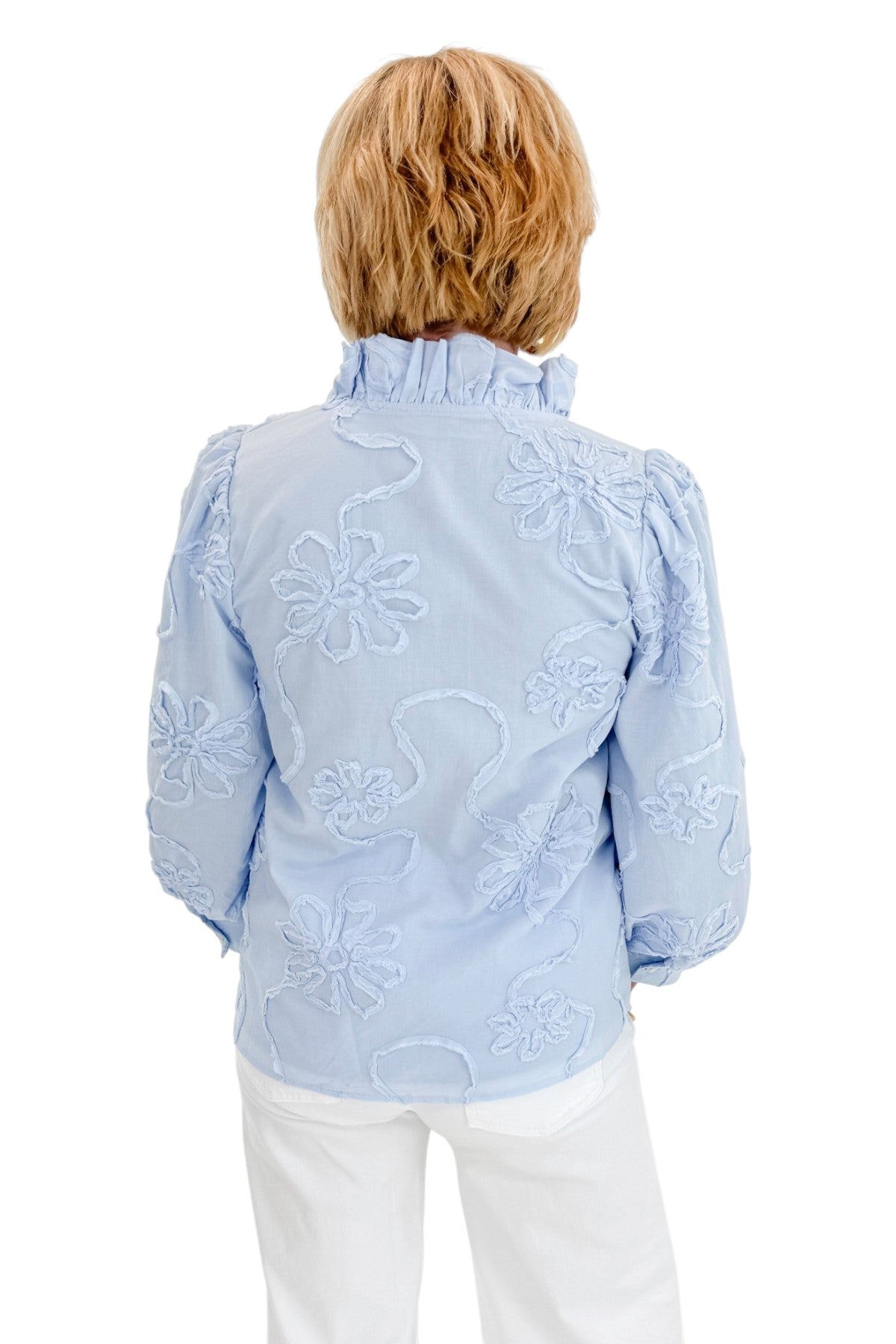 Back view of woman wearing Swagger Boutique’s Light Blue Floral 3/4 Sleeve Embroidered Top with jeans against white studio background.