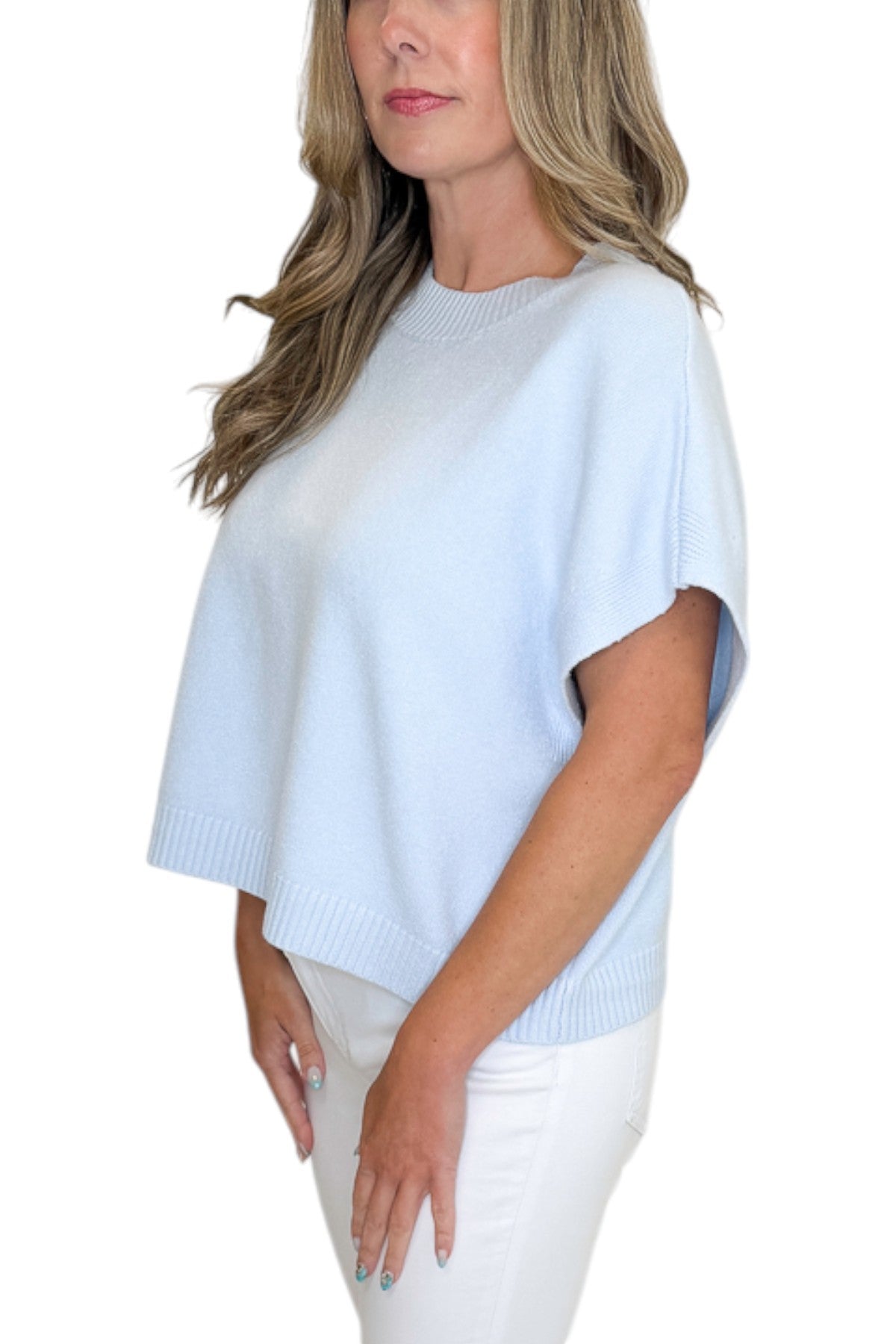 Side detail view of woman wearing Swagger Boutique’s Light Blue Light Weight Short Sleeve Sweater with jeans against white studio background.