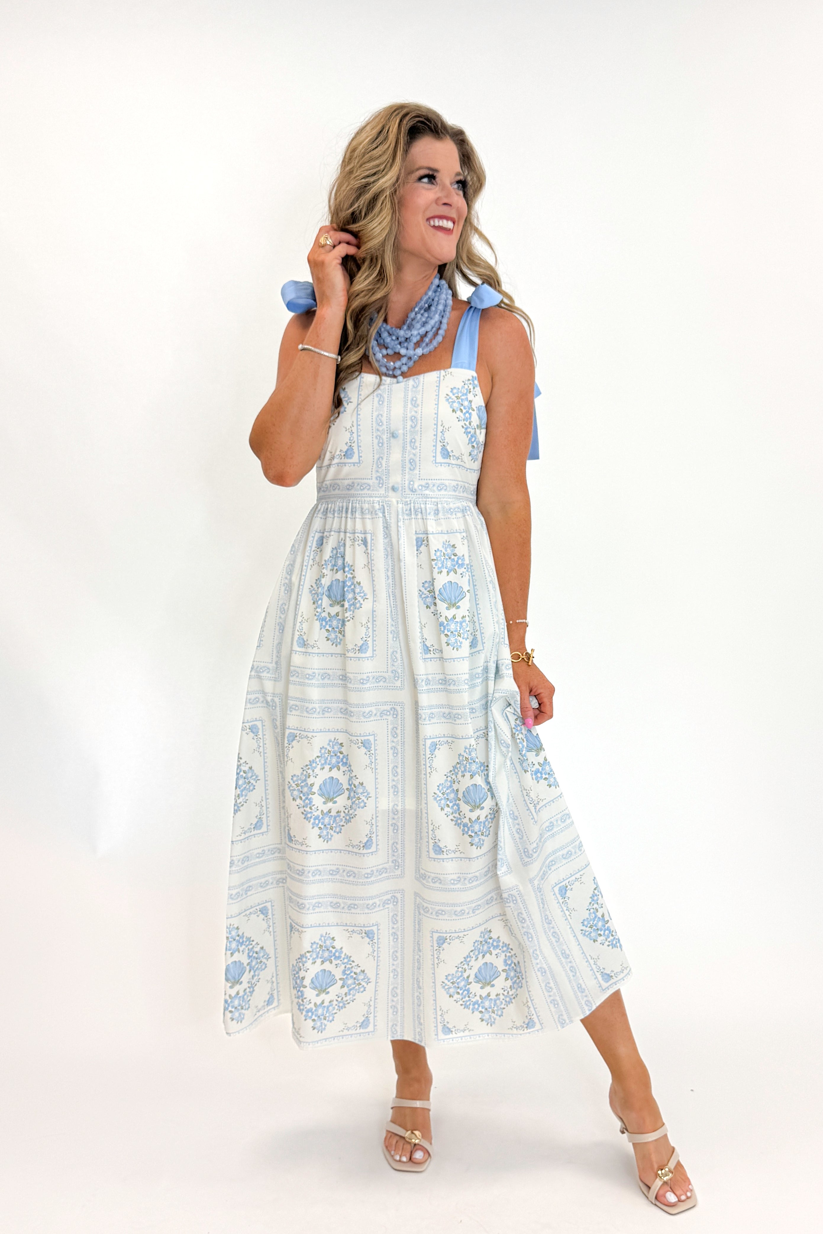 Front view of woman wearing Swagger Boutique’s Light Blue Printed Midi Dress With Tie Straps by Entro with heels against white studio background.