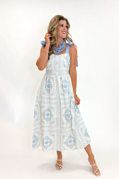 Front view of woman wearing Swagger Boutique’s Light Blue Printed Midi Dress With Tie Straps by Entro with heels against white studio background.