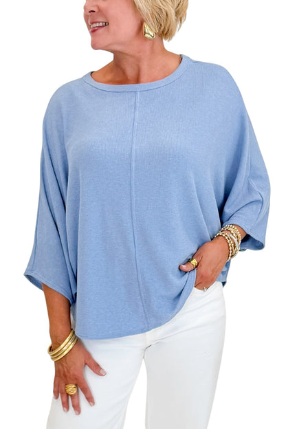 Front detail view of woman wearing Swagger Boutique’s Light Blue Ribbed Dolman Sleeve Top with jeans against white studio background.