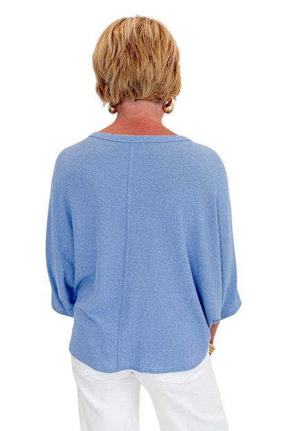 Back view of woman wearing Swagger Boutique’s Light Blue Ribbed Dolman Sleeve Top with jeans against white studio background.