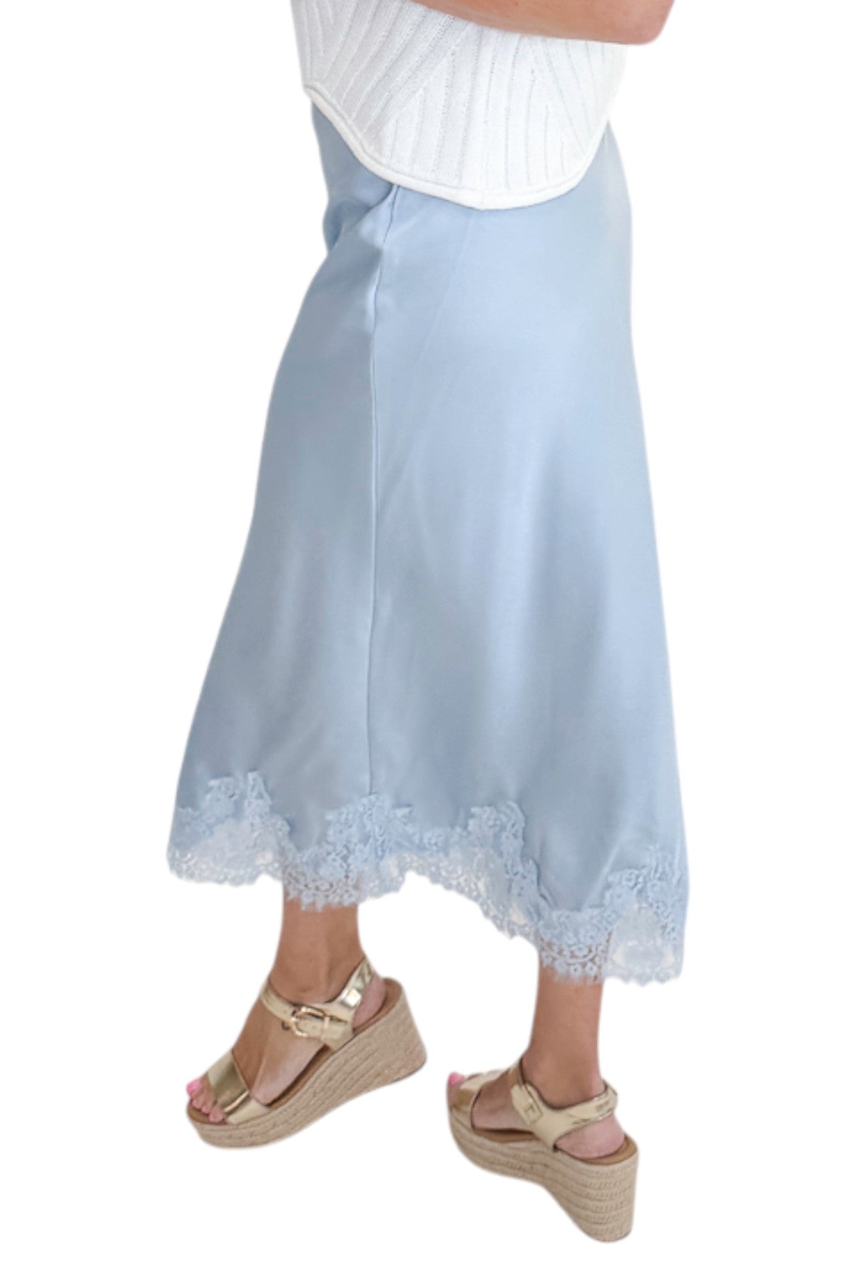Side detail view of woman wearing Swagger Boutique’s Light Blue Satin &amp; Lace Midi Skirt with sweater against white studio background.