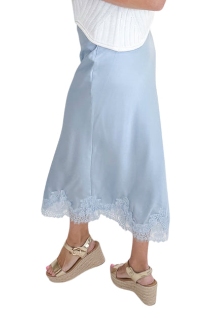 Side detail view of woman wearing Swagger Boutique’s Light Blue Satin &amp; Lace Midi Skirt with sweater against white studio background.