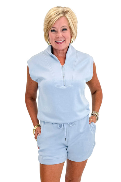 Front view of woman wearing Swagger Boutique’s Light Blue Sleeveless 1/4 Zip Top with matching shorts against white studio background.