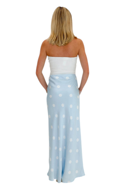Back view of woman wearing Swagger Boutique’s Light Blue &amp; White Polka Dot Satin Skirt with white top against white studio background.