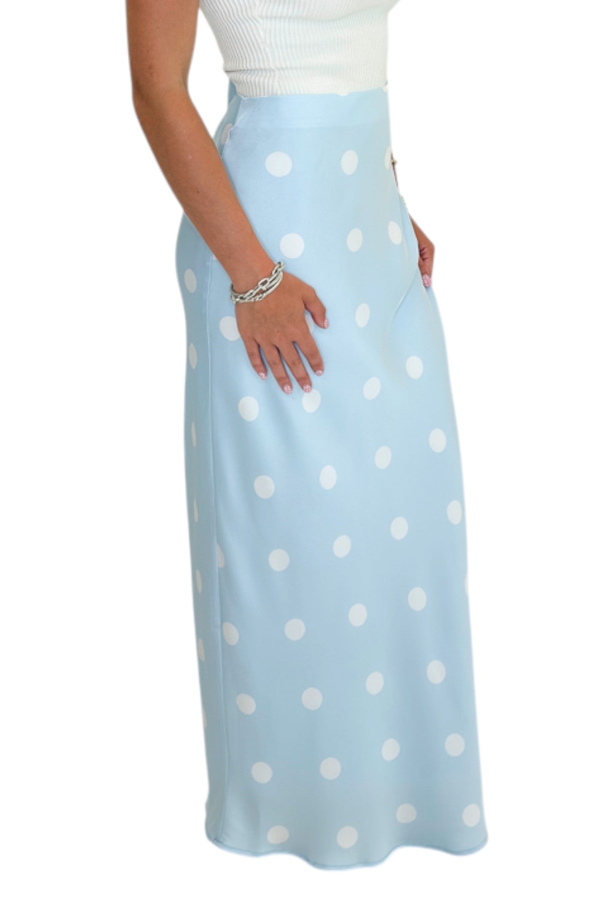 Side view of woman wearing Swagger Boutique’s Light Blue &amp; White Polka Dot Satin Skirt with white top against white studio background.