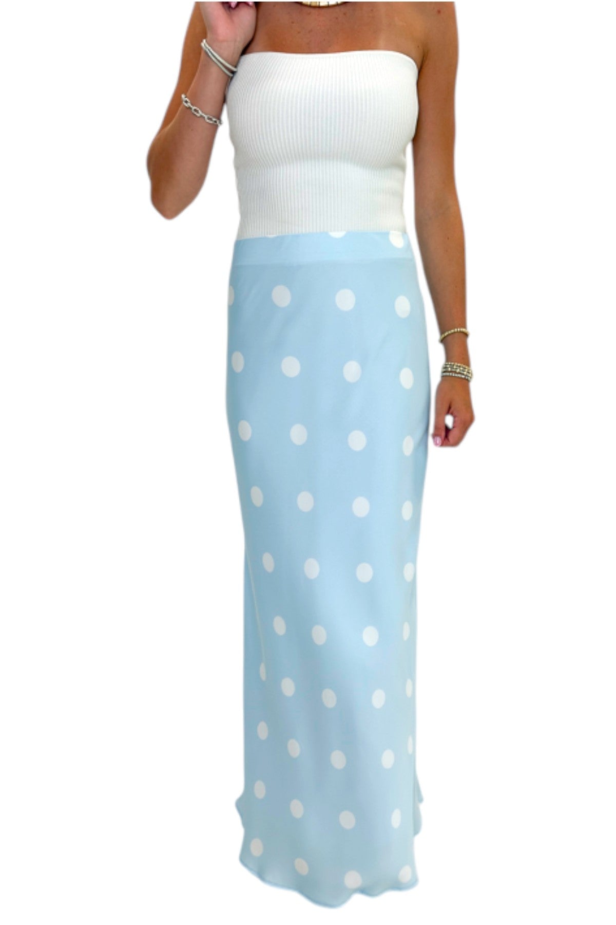 Front detail view of woman wearing Swagger Boutique’s Light Blue &amp; White Polka Dot Satin Skirt with white top against white studio background.