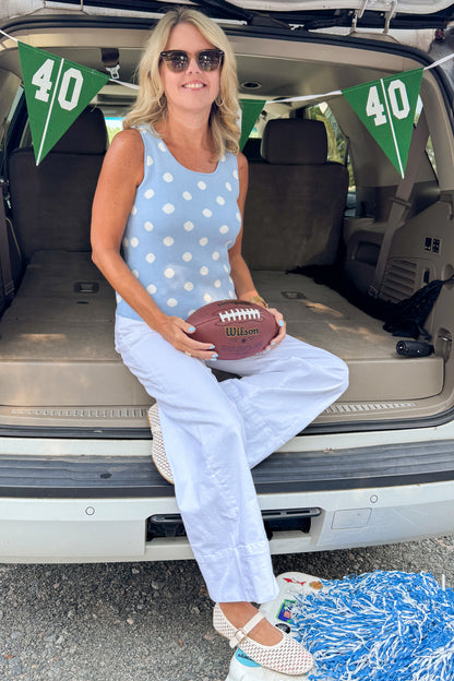 Front view of woman wearing Swagger Boutique’s Light Blue &amp; White Polka Dot Sweater Tank with jeans sitting at a football tailgate.