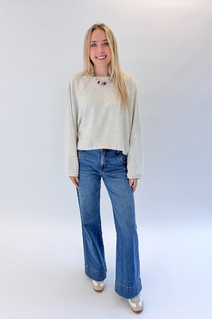 Front view of woman wearing Swagger Boutique’s Light Grey Cropped Sweatshirt with jeans against white studio background.