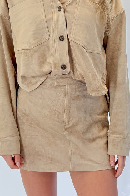 Front detail view of woman wearing Swagger Boutique’s Light Sand All Day Cropped Suede Jacket and mini skirt by Z Supply against white studio background.