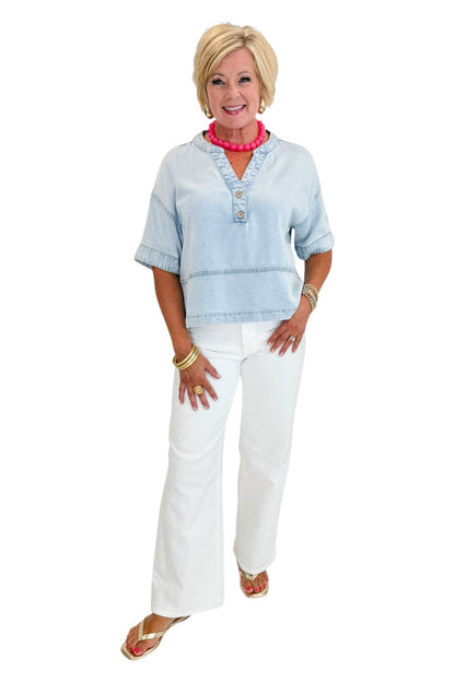 Front view of woman wearing Swagger Boutique’s Light Wash Denim V-Neck Top with jeans against white studio background.